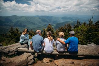 group of people sitting on rocks overlooking mountain by Roberto Nickson courtesy of Unsplash.