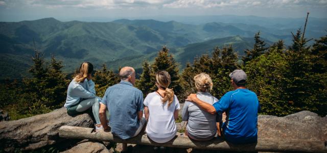 group of people sitting on rocks overlooking mountain by Roberto Nickson courtesy of Unsplash.